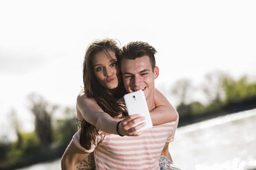 Verspieltes junges Paar nimmt Selfie im Freien - UUF003876
