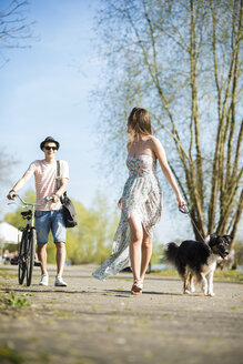 Junges Paar beim Spaziergang mit Hund im Freien im Sommer - UUF003879