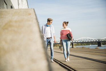 Junger Mann und Frau gehen am Flussufer spazieren - UUF003881