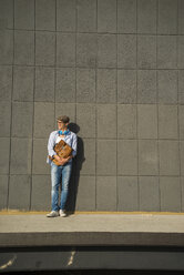 Junger Mann mit Tasche auf dem Bahnsteig stehend - UUF003890