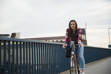 Junge Frau fährt Fahrrad auf einer Brücke - UUF003915