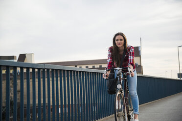 Young woman riding bicycle on bridge - UUF003915