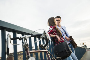 Junger Mann und Frau mit Fahrrad auf Brücke - UUF003916