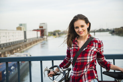 Deutschland, Mannheim, junge Frau mit Fahrrad auf Brücke - UUF003922