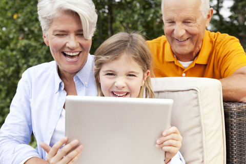 Glückliche Großeltern und Mädchen im Freien mit digitalem Tablet, lizenzfreies Stockfoto