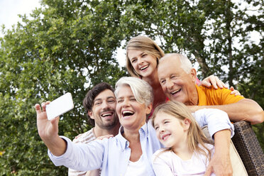 Happy extended family taking cell phone picture outdoors - MFRF000166