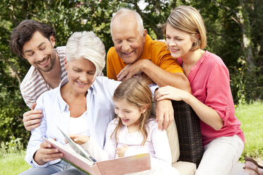 Glückliche Großfamilie mit Buch im Freien - MFRF000167