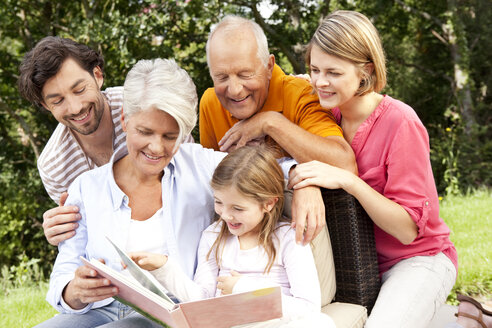 Glückliche Großfamilie mit Buch im Freien - MFRF000167