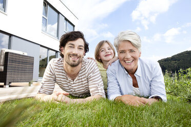 Porträt einer glücklichen Großmutter, eines Vaters und eines Mädchens auf dem Rasen liegend - MFRF000174