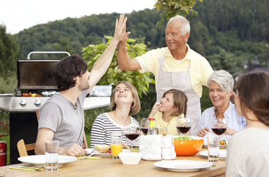 Adult son high fiving father at barbecue party - MFRF000205