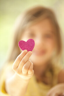 Close-up of girl holding glittering heart - MFRF000192