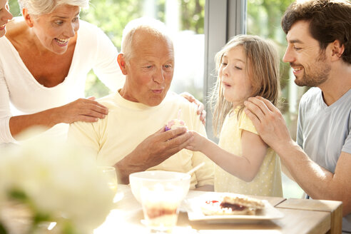 Senior man with his family blowing out birthday candle - MFRF000195