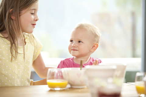 Baby girl with sister at breakfast table stock photo