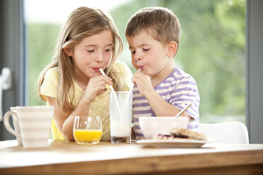 Brother and sister sharing glass of milk - MFRF000197