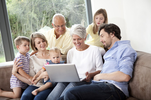 Extended family on couch using laptop stock photo