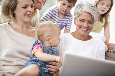 Großfamilie auf der Couch mit Laptop, lizenzfreies Stockfoto