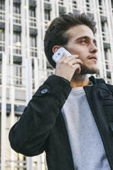 Spain, Madrid, young man on cell phone in front of a building - ABZF000017