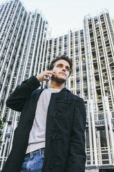 Spain, Madrid, young man on cell phone in front of a building - ABZF000010