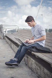 Spanien, Ferrol, junger Mann benutzt einen Laptop im Freien - RAEF000147