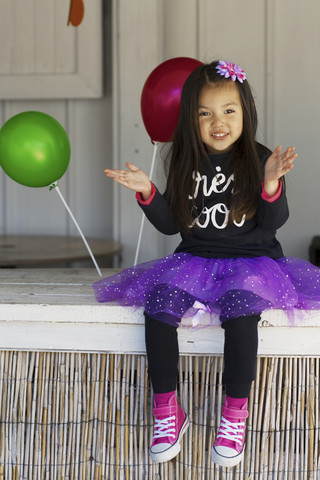 Kleines Mädchen mit Luftballons sitzend, lizenzfreies Stockfoto