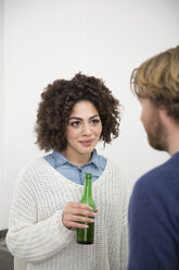 Junge Frau hält Bierflasche und sieht Mann an - FKF000956