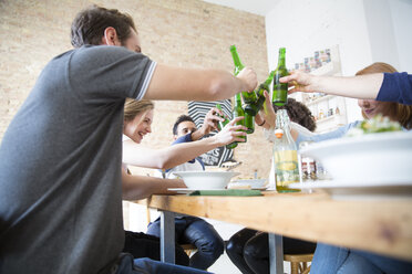 Glückliche Freunde, die zusammen essen und auf Bierflaschen anstoßen - FKF001000