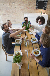 Happy friends eating together clinking beer bottles - FKF001001