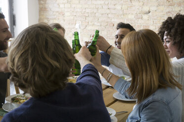Glückliche Freunde, die zusammen essen und auf Bierflaschen anstoßen - FKF000960