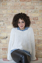 Portrait of young woman in front of brick wall - FKF000971