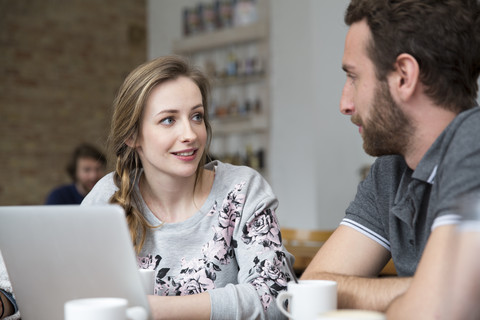 Junger Mann und Frau mit Laptop in einer Cafeteria, lizenzfreies Stockfoto