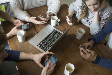 Eine Gruppe von Freunden benutzt Smartphones in einer Cafeteria - FKF001026
