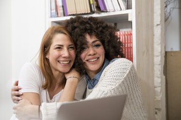 Two happy female with laptop embracing - FKF001017