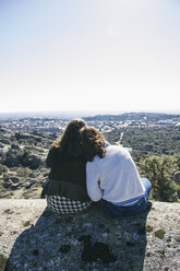 Spanien, Torrelodones, zwei Freundinnen sitzen nebeneinander auf einem Felsen und betrachten die Aussicht - ABZF000020