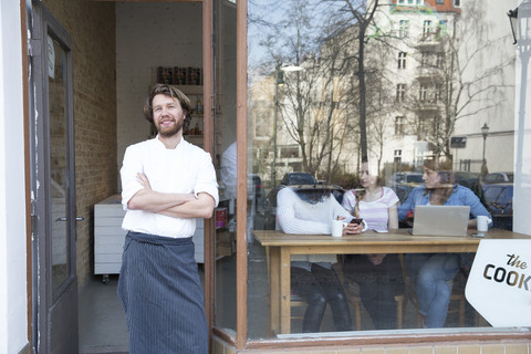 Deutschland, Berlin, Besitzer und Koch eines Bistros stehen vor der Eingangstür, lizenzfreies Stockfoto