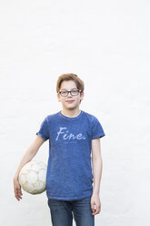 Portrait of boy with soccer ball in front of white house facade - LVF003260