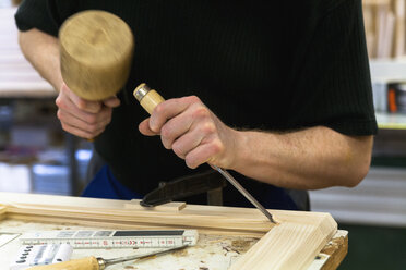 Rahmenbauer bei der Arbeit an einem Holzrahmen mit Hammer und Meißel - TCF004648