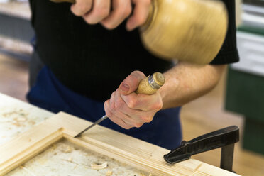 Rahmenbauer bei der Arbeit an einem Holzrahmen mit Hammer und Meißel - TCF004649