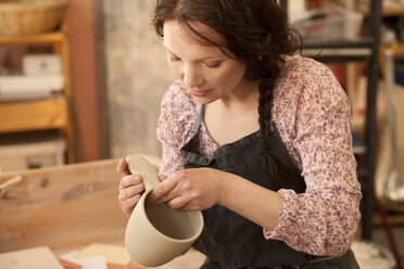 Potter in workshop working on earthenware pot - MAEF010351