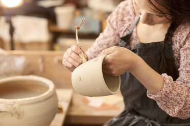 Potter in workshop working on earthenware pot - MAEF010353