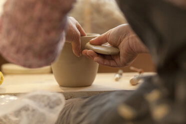 Potter in workshop working on earthenware pot - MAEF010354