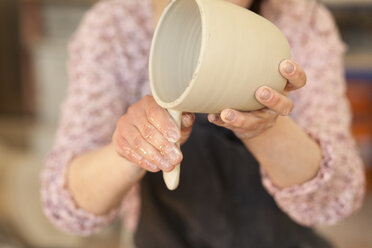 Potter in workshop working on earthenware pot - MAEF010355