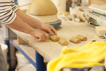 Potter in workshop cutting clay - MAEF010360