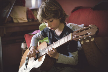 Porträt eines kleinen Jungen, der zu Hause akustische Gitarre spielt - RAEF000155