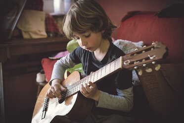 Portrait of little boy playing acoustic guitar at home - RAEF000155