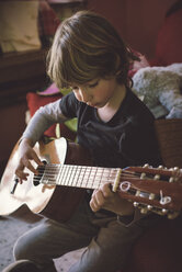 Little boy playing acoustic guitar at home - RAEF000157