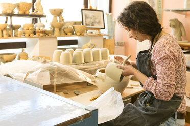 Potter in workshop working on earthenware pot - MAEF010367