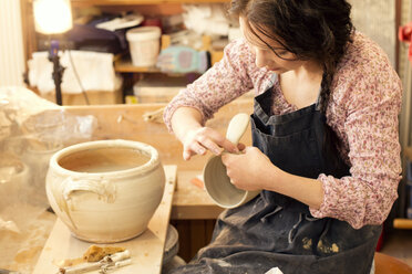 Potter in workshop working on earthenware pot - MAEF010370