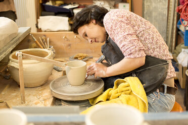 Potter in workshop working on potters wheel - MAEF010376