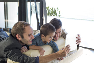 Zwei Männer mit Kind schauen auf ein digitales Tablet - ZEF004433