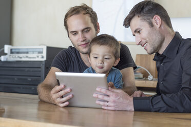 Two men with kid looking at digital tablet - ZEF004448